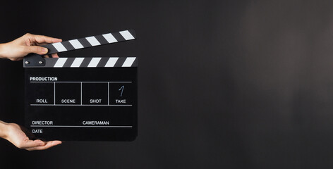 A clapboard used in movies and tv-shows in a black background.